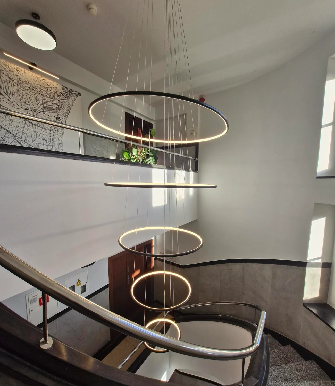 Zobacz czarną lampę Led Orbit No.5 zawieszoną na klatce schodowej w eleganckim wnętrzu